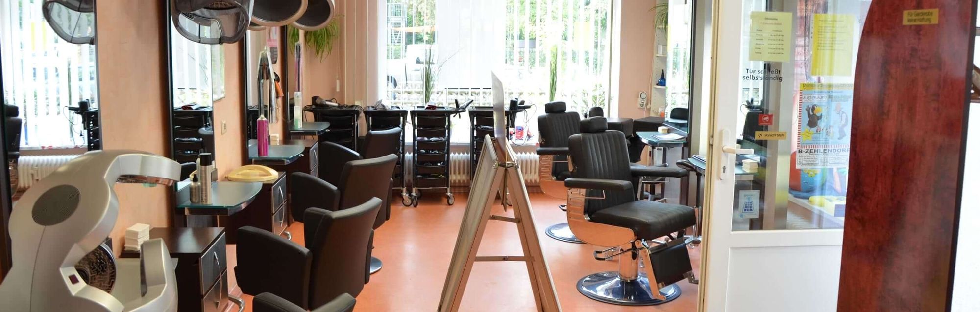 Ein heller, einladender Friseursalon mit Styling-Stühlen, Spiegeln und moderner Ausstattung, bereit für die Kunden.